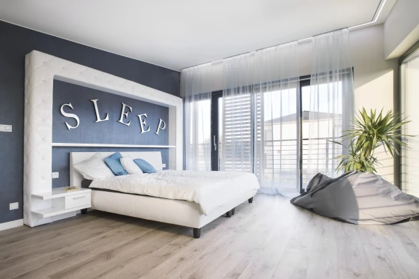 A bedroom with blue walls ventilated by Inventer decentralised ventilation