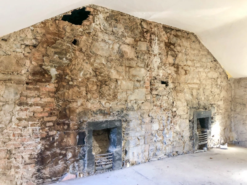 Exposed stone wall showing old fireplaces