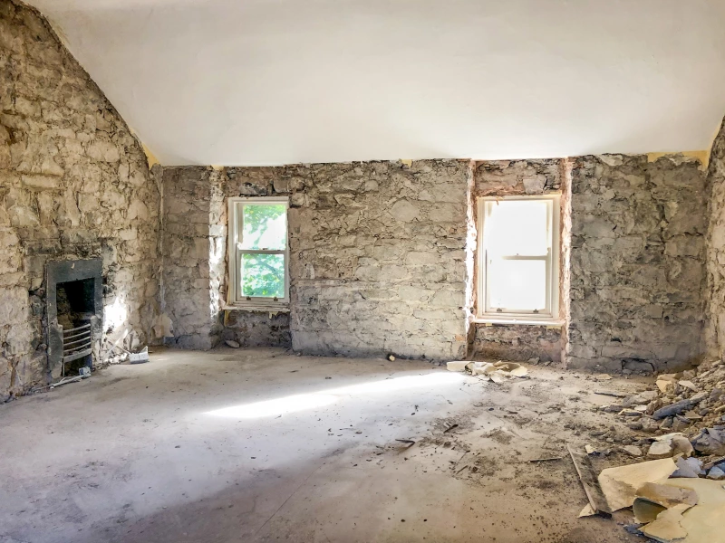 Exposed stone wall showing two windows with original window glass from previous occupancy