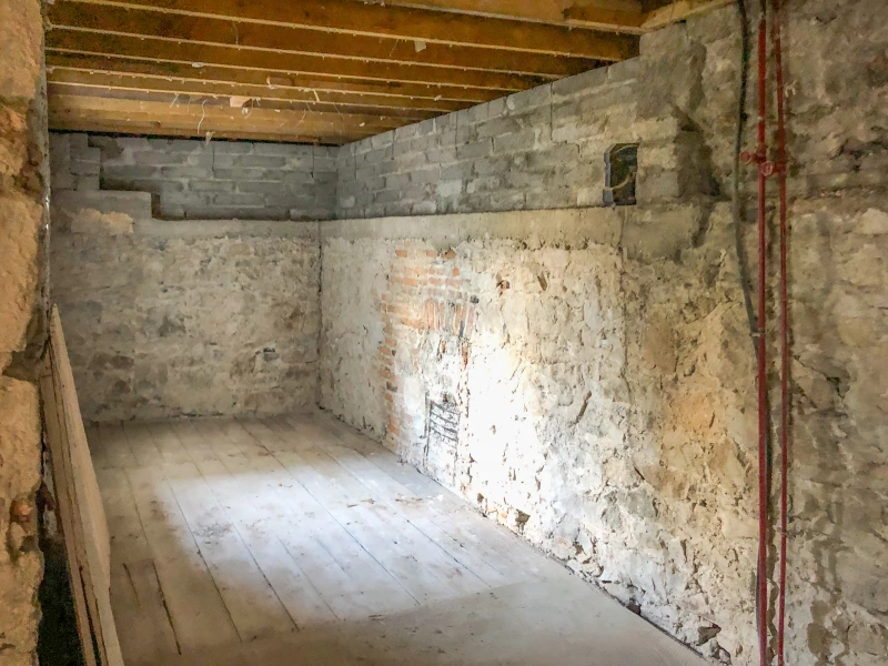 Long room with exposed stone wall and floorboards intact