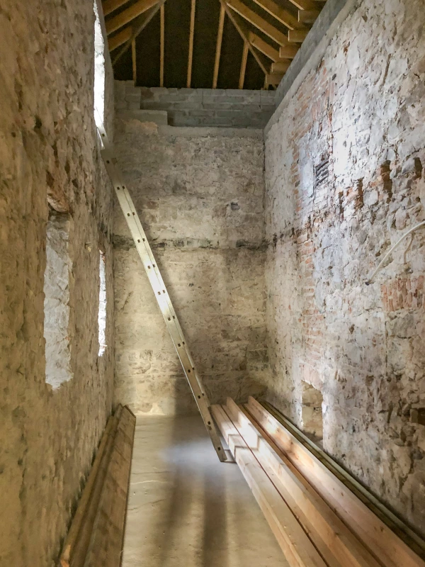 Long room with exposed stone wall and floorboards intact, newly replaced roof.