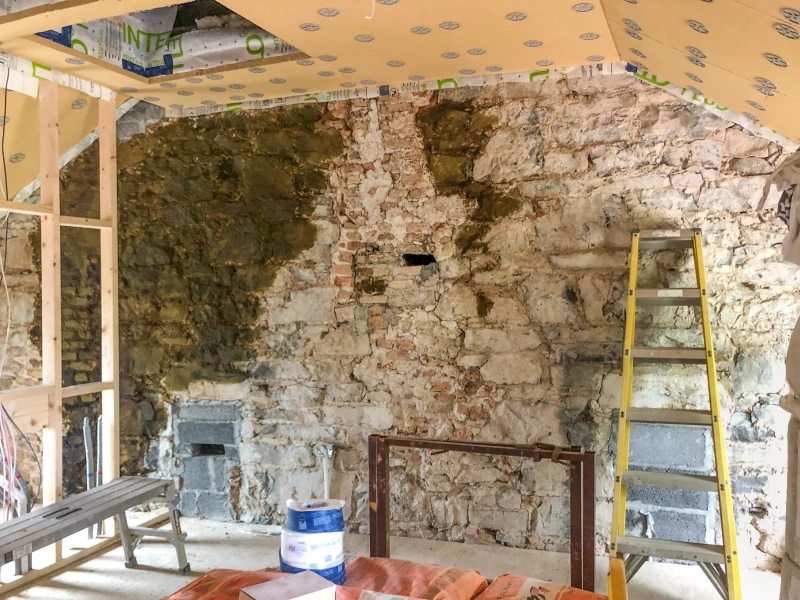 Woodfibre boards fitted to ceiling rafters around attic opening with Diathonite Evolution partly applied to stone wall.